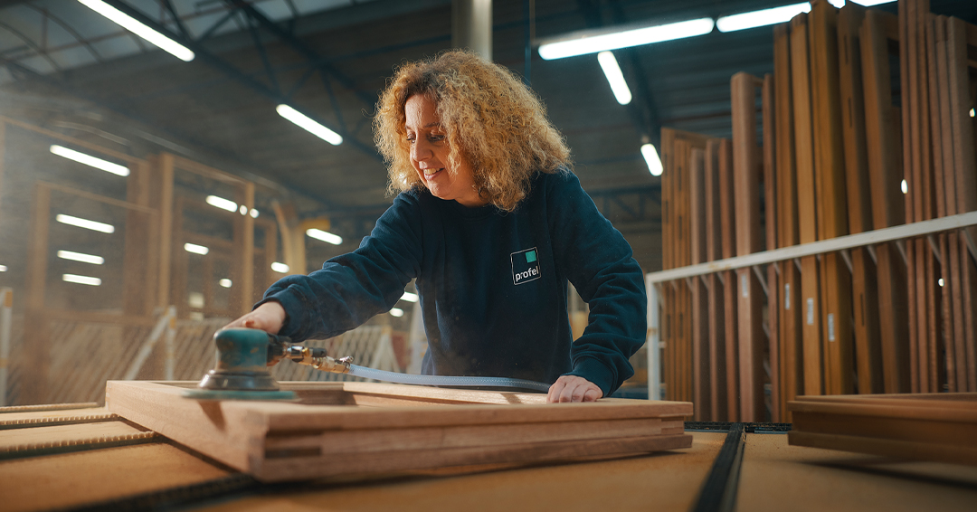 Profel-medewerkster schuurt houten schrijnwerk in de houtafdeling